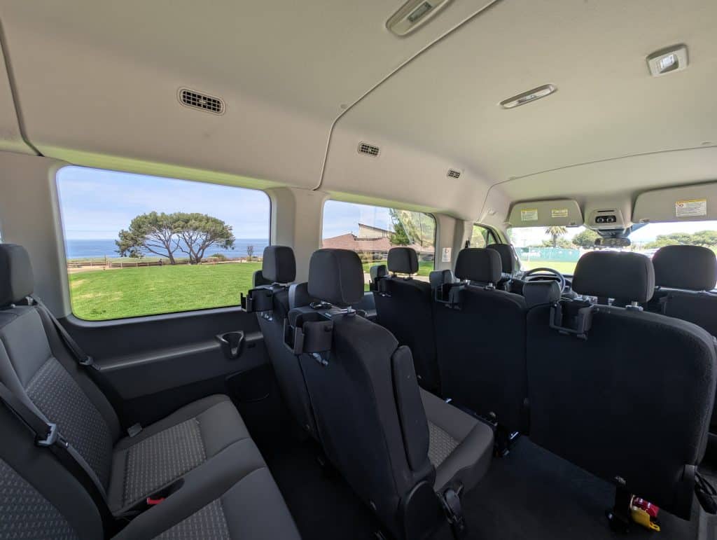 Heller Innenraum des Vista-Tours Tour-Vans mit großen Fenstern und Smartphonehaltern an den Sitzplätzen